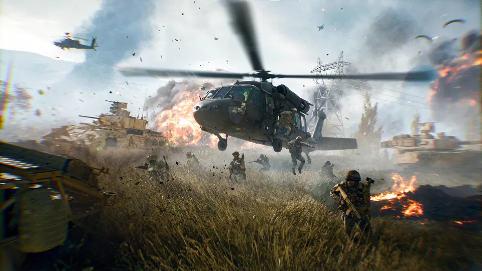 Battlefield 6: vojáci seskakují z vrtulníku Black Hawk na travnatém poli mezi tanky a explozemi.