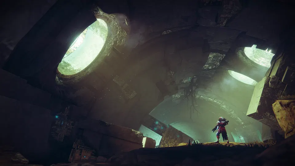 Destiny 2: postava stojí na kamenné plošině pod velkými zářícími otvory v ruinové stavbě