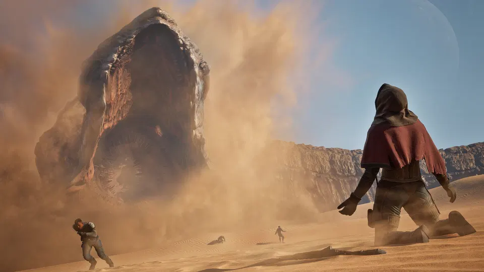 Dune: Awakening – postava v červeném plášti hledí na obrovského červa vynořujícího se z písku