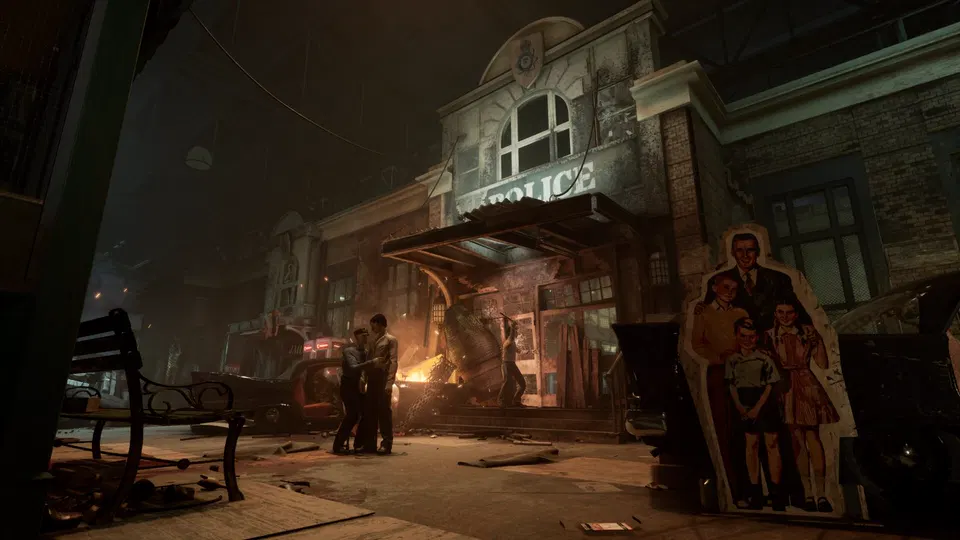 The Outlast Trials: noční ulice před budovou s nápisem, hoří světlo a u vchodu stojí dvě postavy